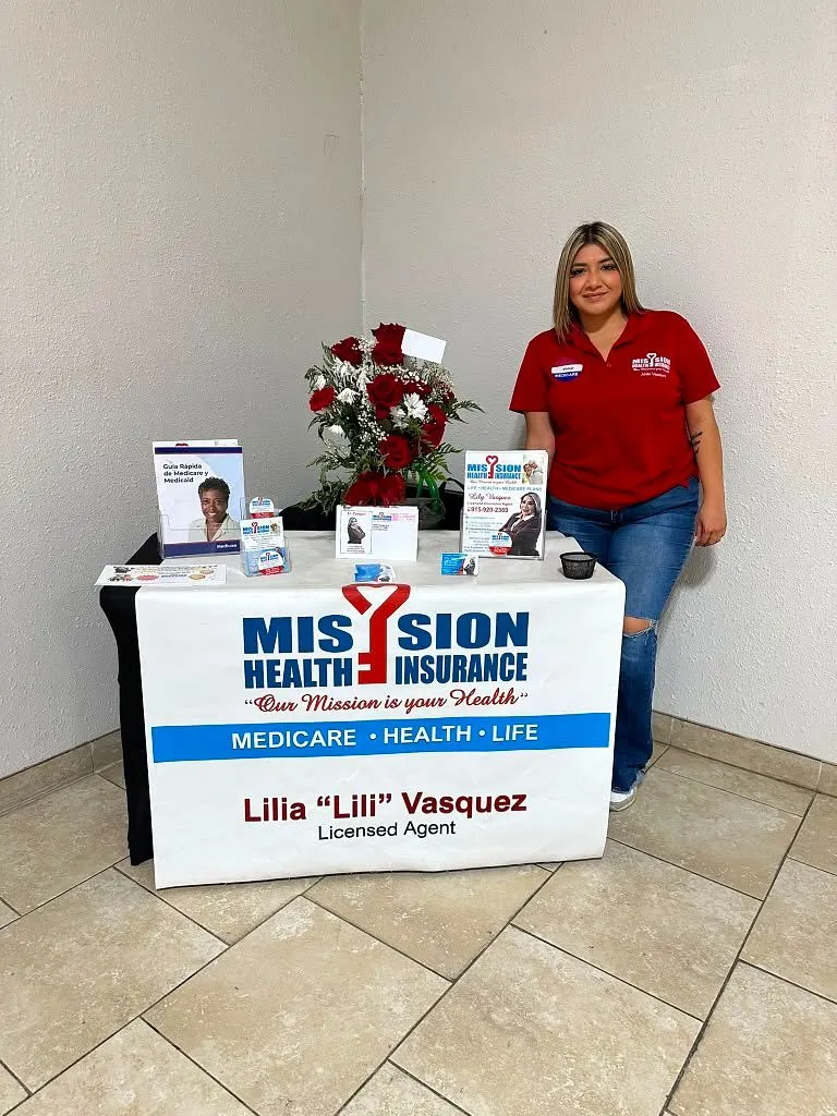 Lily Vásquez en el stand de Mission Health Insurance con flores